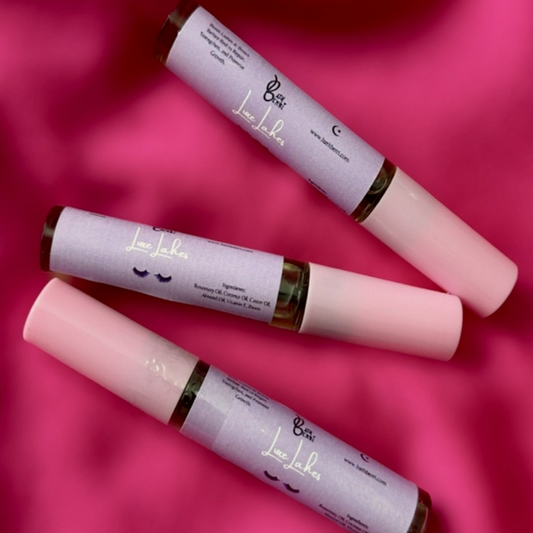 Three tubes of Natural brush-on lash oil with castor oil and vitamin E on a pink surface, with eye lash graphics on the labels.
