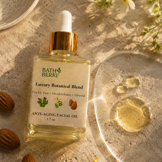 Bath Berri Luxury Botanical Blend Anti-Aging Facial Oil in a clear dropper bottle with a gold collar, styled on a sandy surface with almonds, white flowers, and a glass dish showing the golden oil.