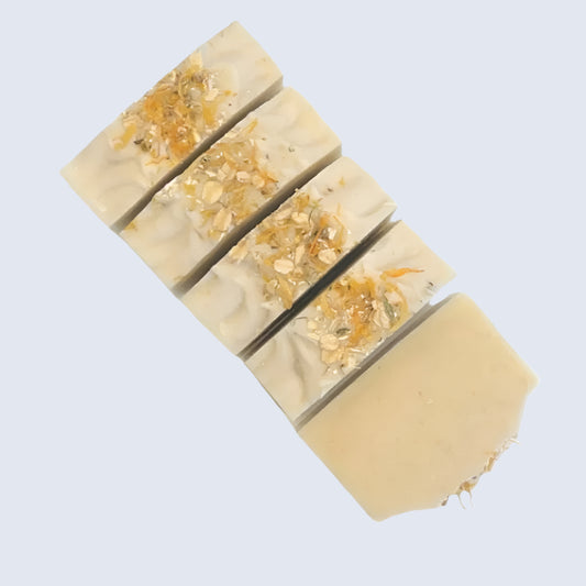 Four stacked soap bars with visible natural ingredients on a white background
