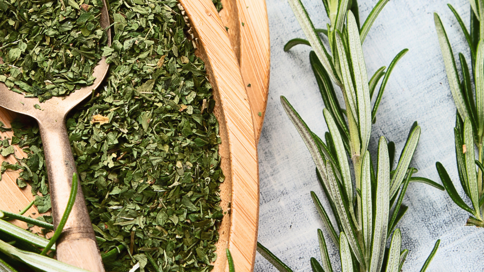Dried rosemary in wooden bowls with fresh rosemary on a light background