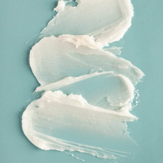 creamy shea butter lip balm smears on a teal background