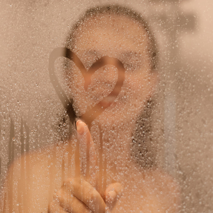 a woman in steamed shower making heart detail with finger