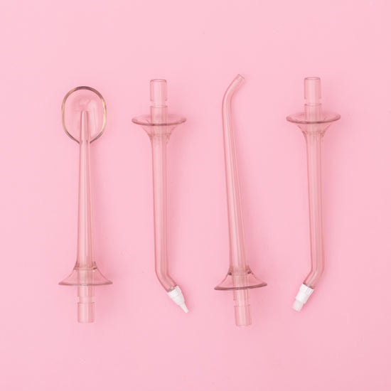 Set of four pink glass dental straws on a pink background