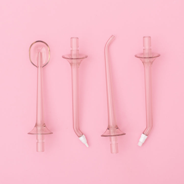 Set of four pink glass dental straws on a pink background