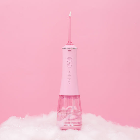 Pink dental water flosser on a pink background