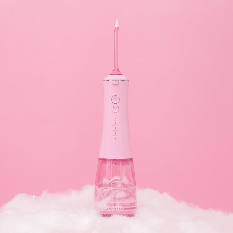 Pink dental water flosser on a pink background