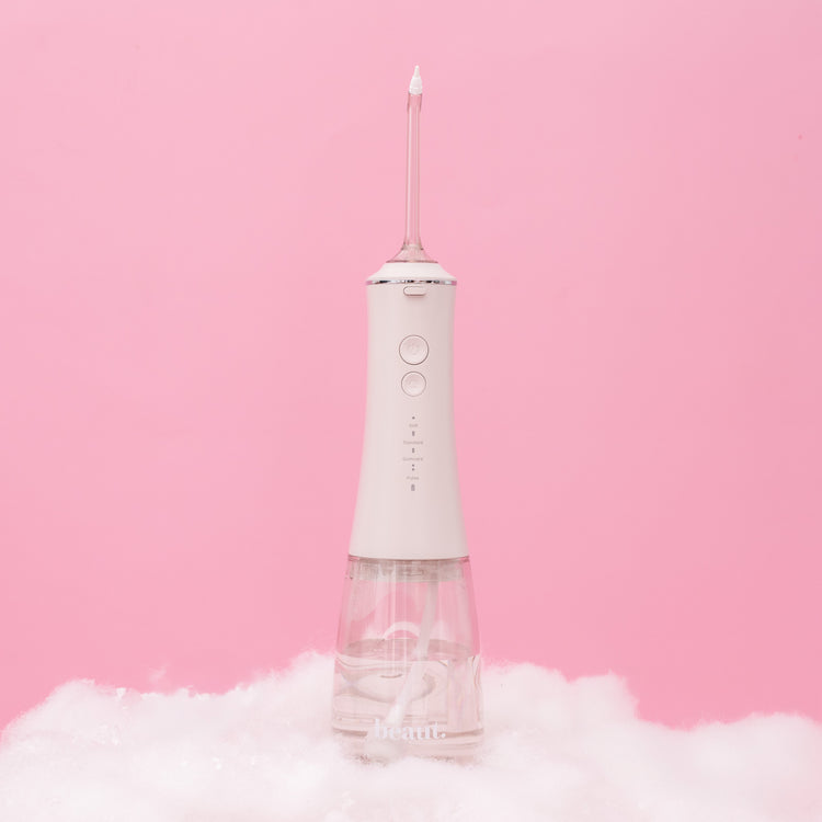 White dental water flosser on a pink background