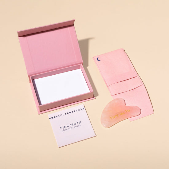Pink Moon skincare product set with a compact mirror, roller, and card on a beige background