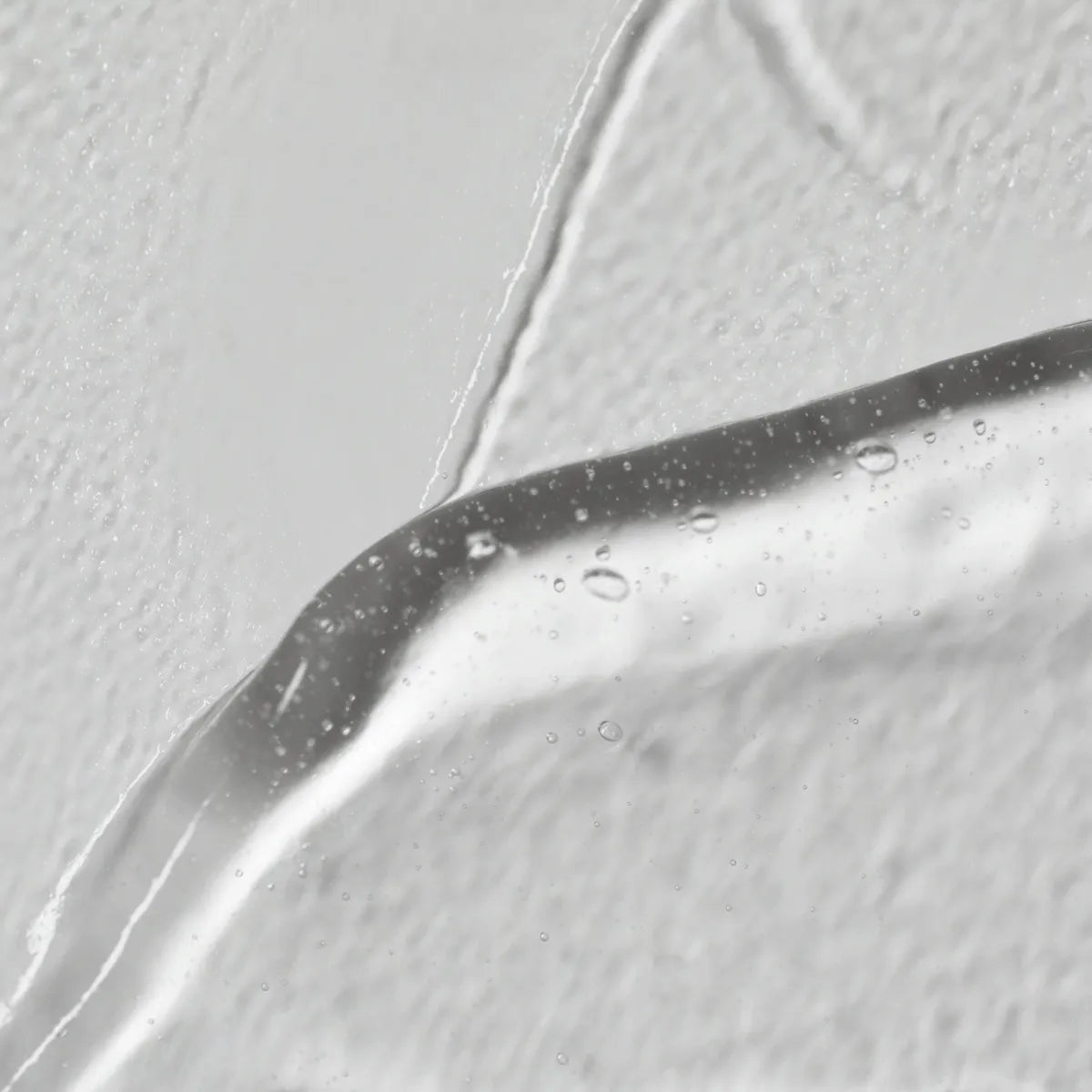Close-up of a droplet on a reflective surface with a light gray background
