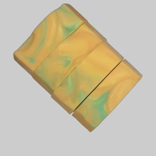 Marbled yellow and green soap bars all in a row of four on a cream white background
