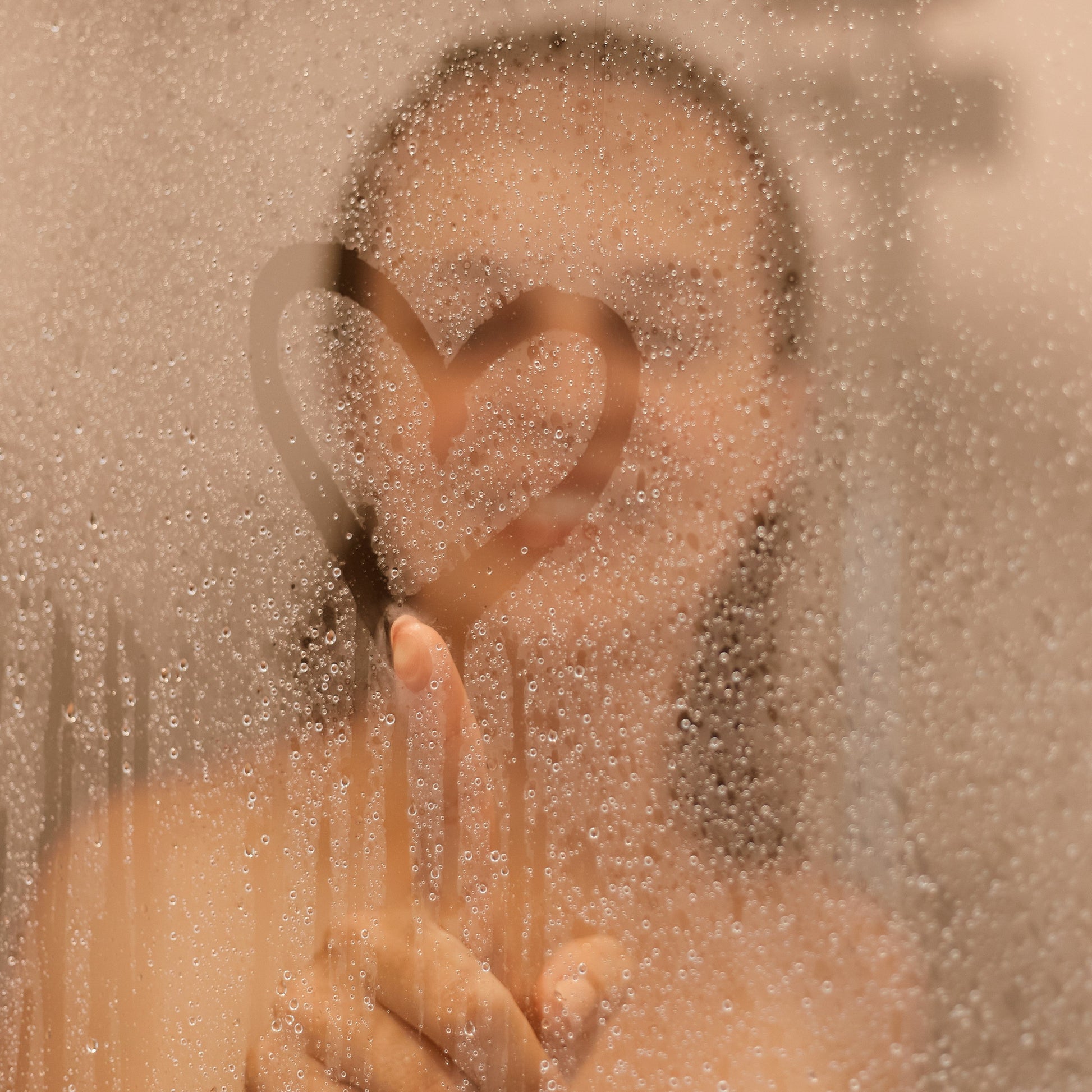 a woman in steamed shower making heart detail with finger