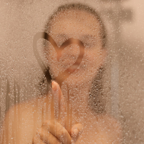 a woman in steamed shower making heart detail with finger